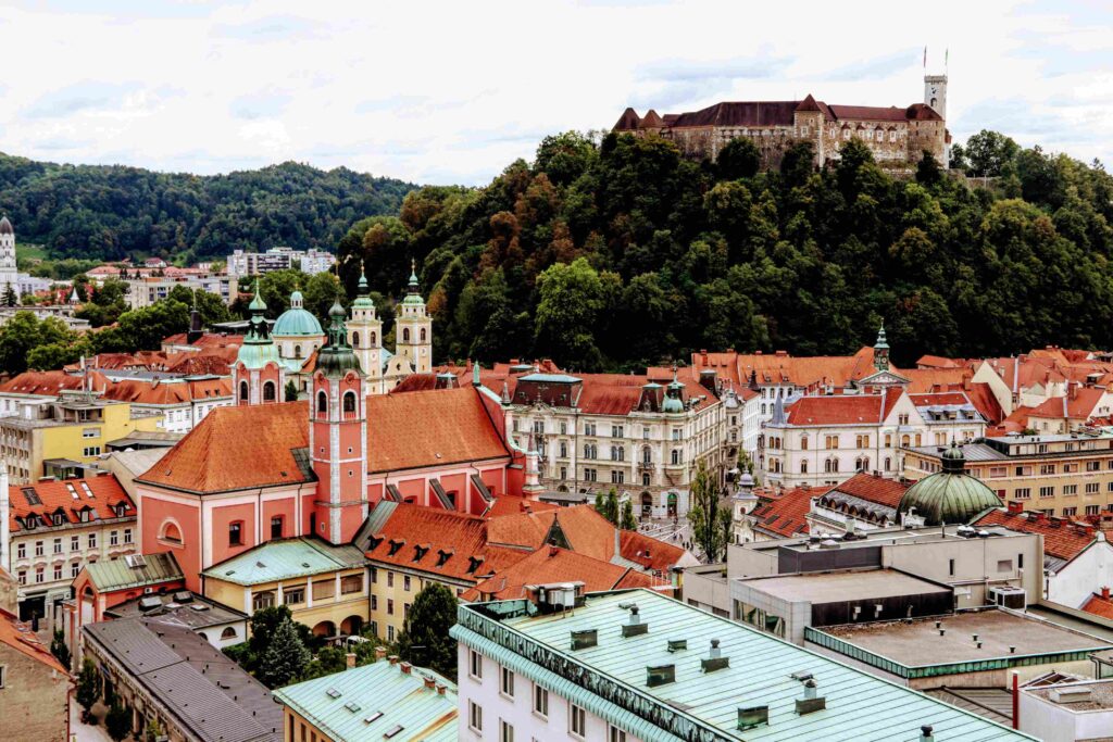 Breathtaking view of Ljubljana, Slovenia, with the Ljubljanica River reflecting colorful Baroque buildings, lush green surroundings, and the iconic Dragon Bridge—top hidden gem for European travel in 2025
